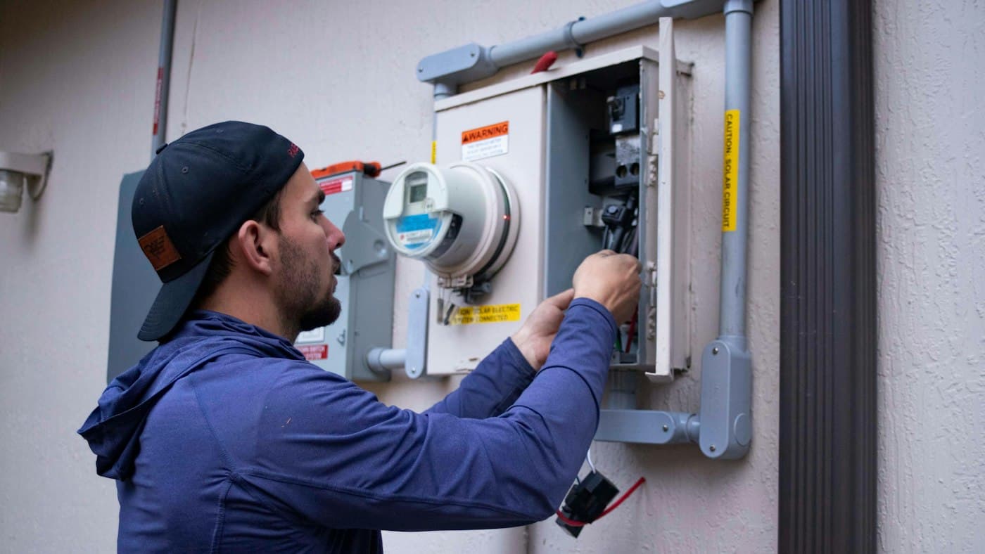 Técnico trabajando en un medidor eléctrico mientras el servicio de contestador con IA de Vossat atiende sus llamadas
